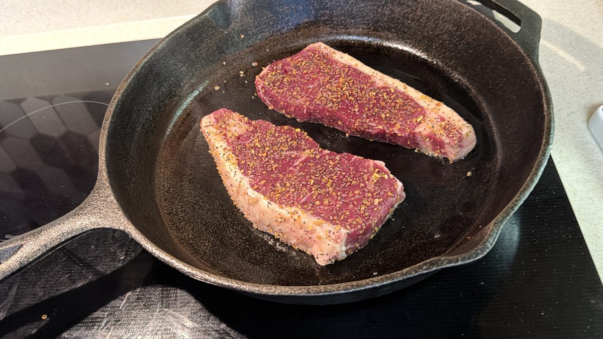 Rigid Ranch steaks searing in a cast-iron skillet